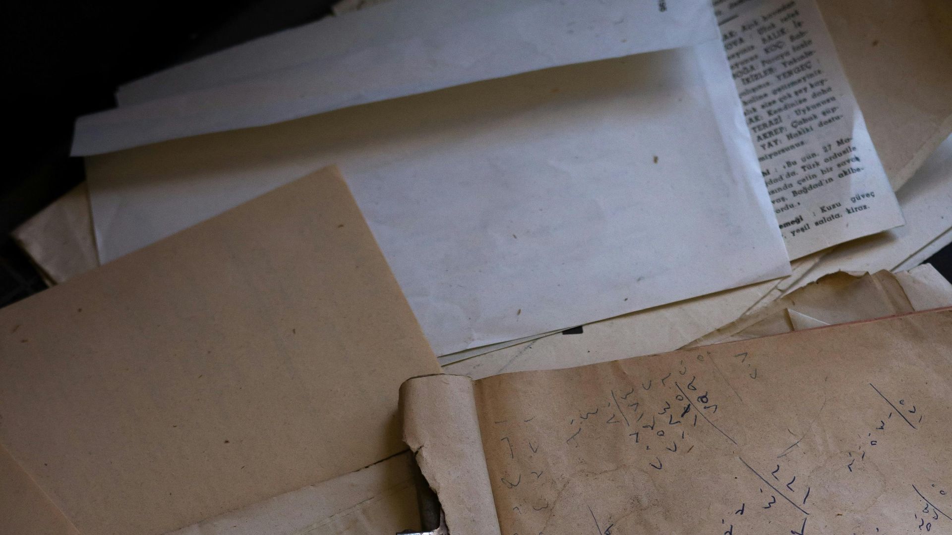 A collection of vintage papers and documents with visible writing and an old clip.