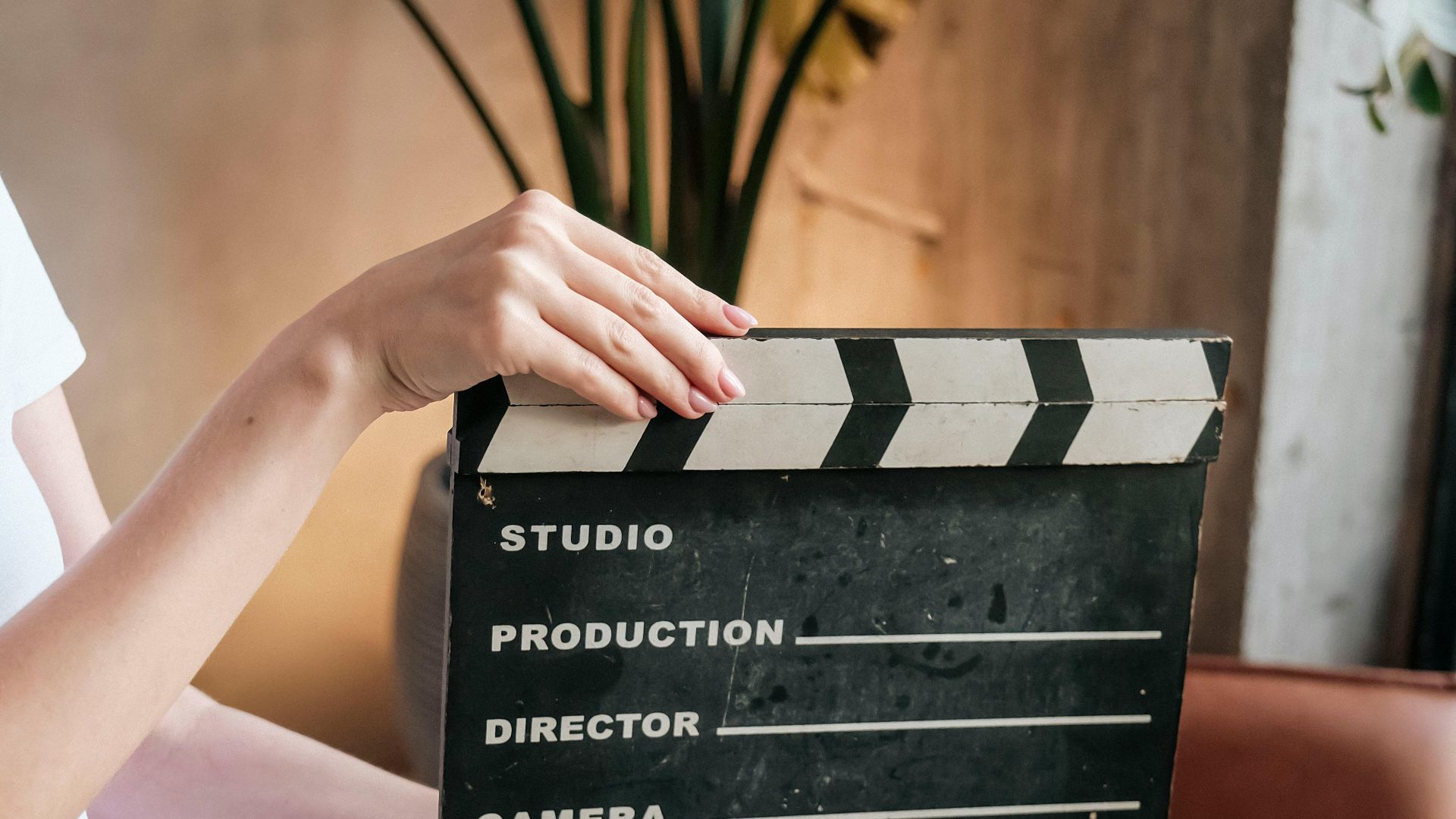 Person holding an empty film clapboard indoors, perfect for movie scenes.