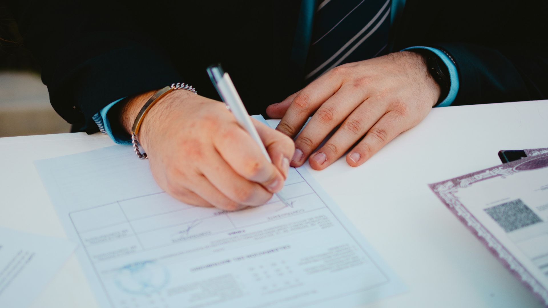 Person signing a document with a pen.