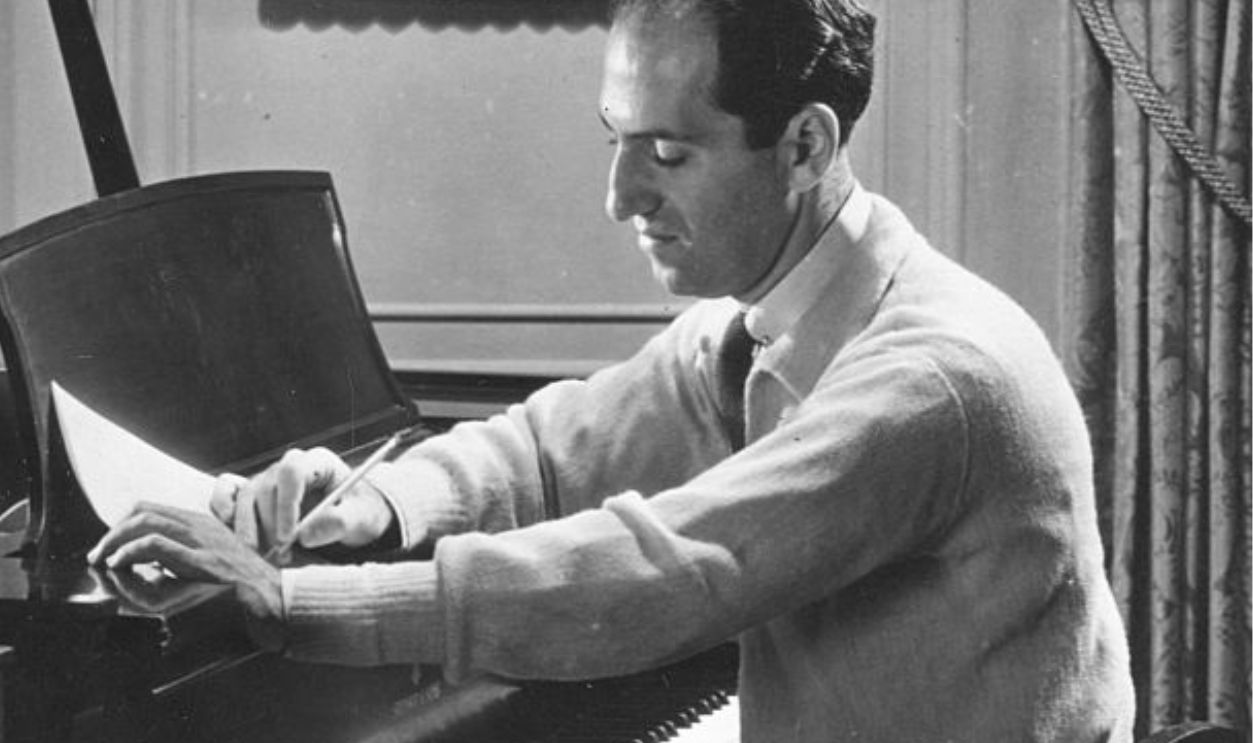 American composer George Gershwin (1989 - 1937) works on a score at the piano in his 72nd Street apartment, New York, New York, 1934.