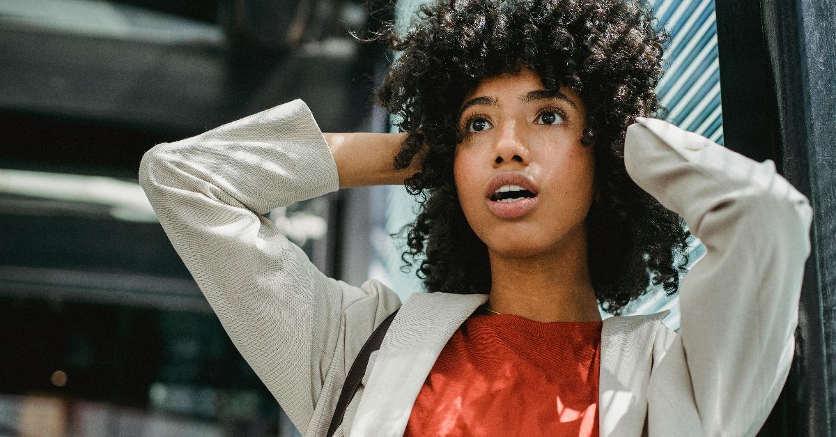Portrait of a surprised young woman with curly hair in an urban setting.