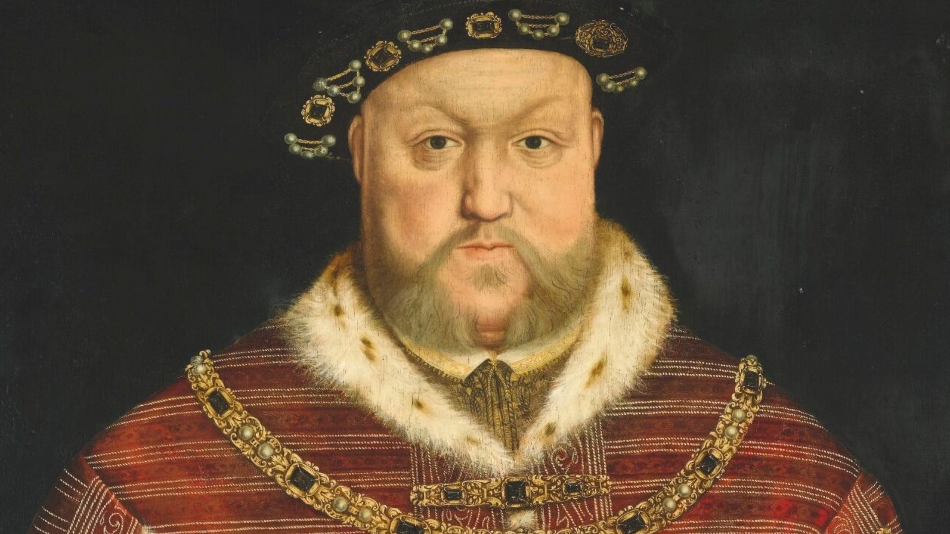 PORTRAIT OF KING HENRY VIII, HALF-LENGTH, WEARING A RICHLY EMBROIDERED RED VELVET SURCOAT, HOLDING A STAFF.