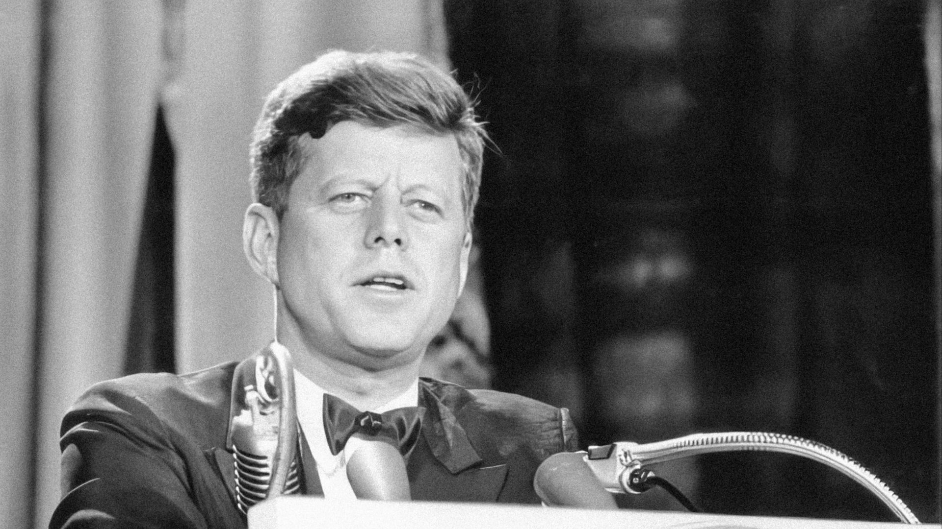 a man in a suit and tie standing at a podium