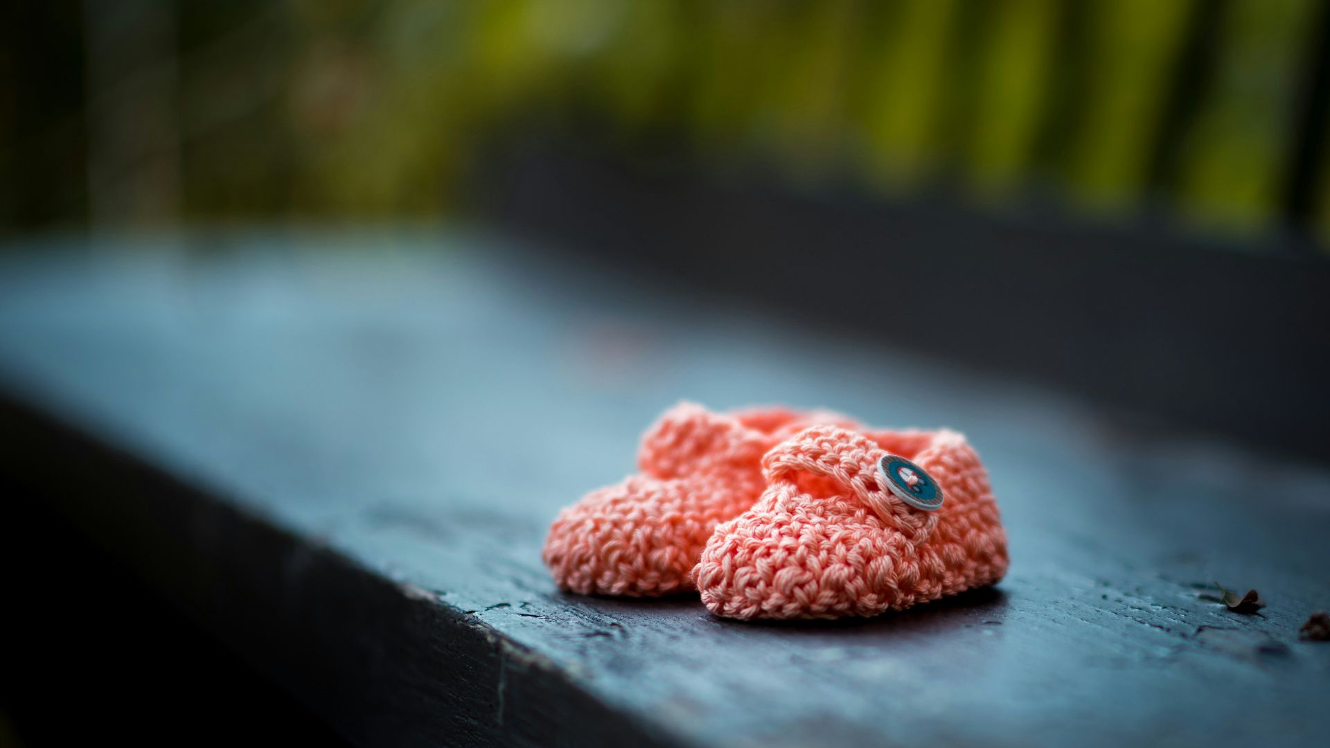 pair of baby's pink knit shoes on bench