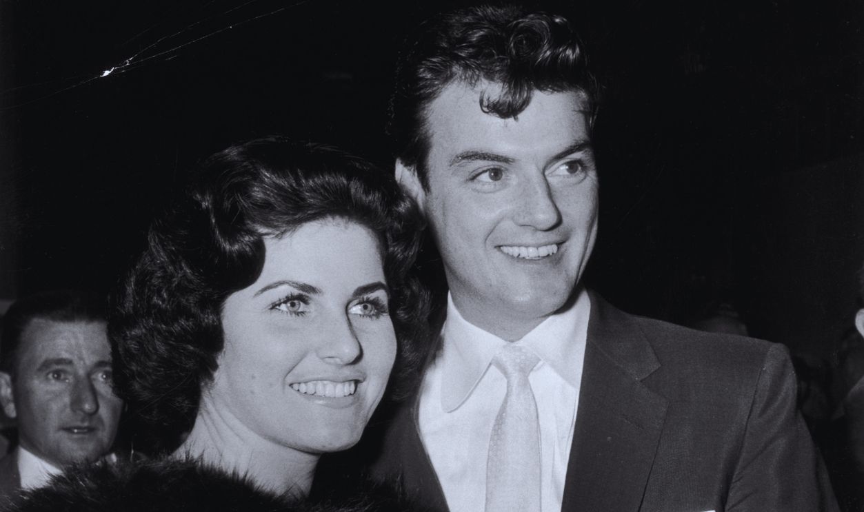Gettyimages - 3233049, William Campbell 1955: American actor William Campbell smiles with his wife Judith Exner Campbell as they attend the premiere of director Jesse Hibbs' film, 'To Hell and Back'. His wife wears a fur stole 