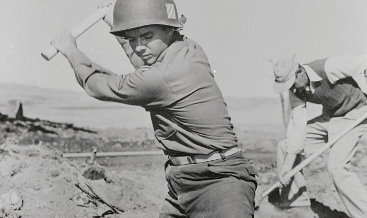 (Original Caption) Film star Sudie Murphy, Congressional Medal of honor winner in World War II and that war's most decorated soldier, goes at ir with a vengeance as he becomes technical advisor and star of the motion picture To Hell and Back. The film is based on his autobiographical book of the same title, about his exploits in the war. Murphy digs a shell crater (above) on a battlefield at the Yakima Firing Center, where parts of the film are being made in cooperation with an entire Battalion of combat-trained soldiers from the 44th infantry Division at Fort Lewis.