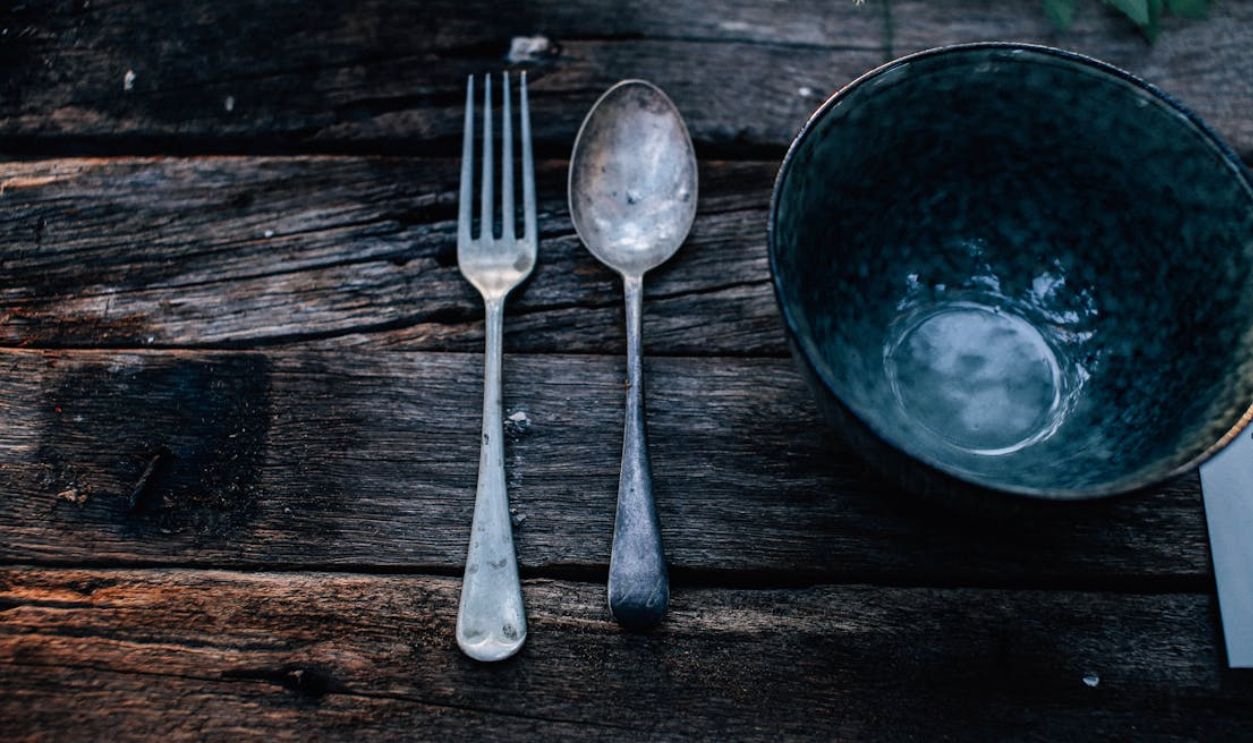 Metal bowl near cutlery on rustic table