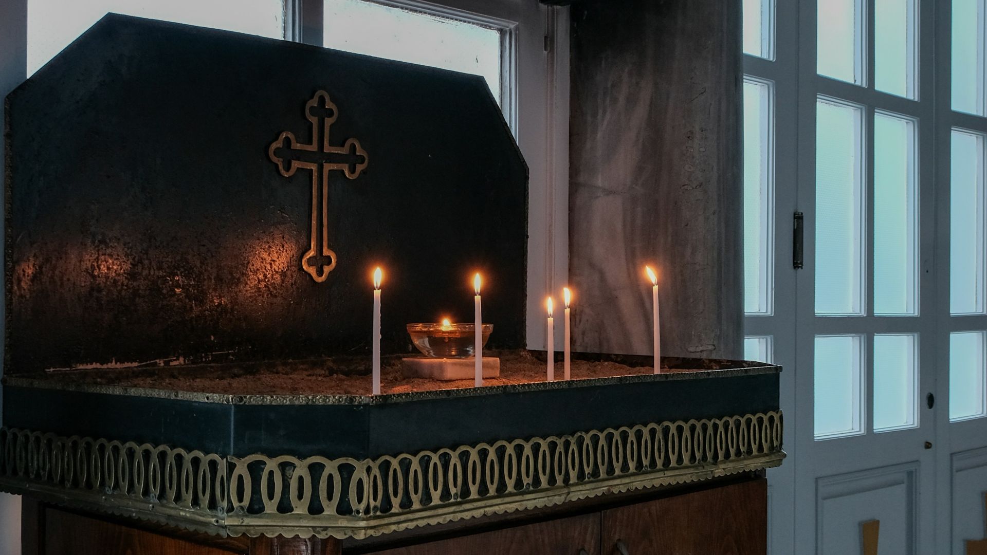 Candles illuminate an altar with a cross.