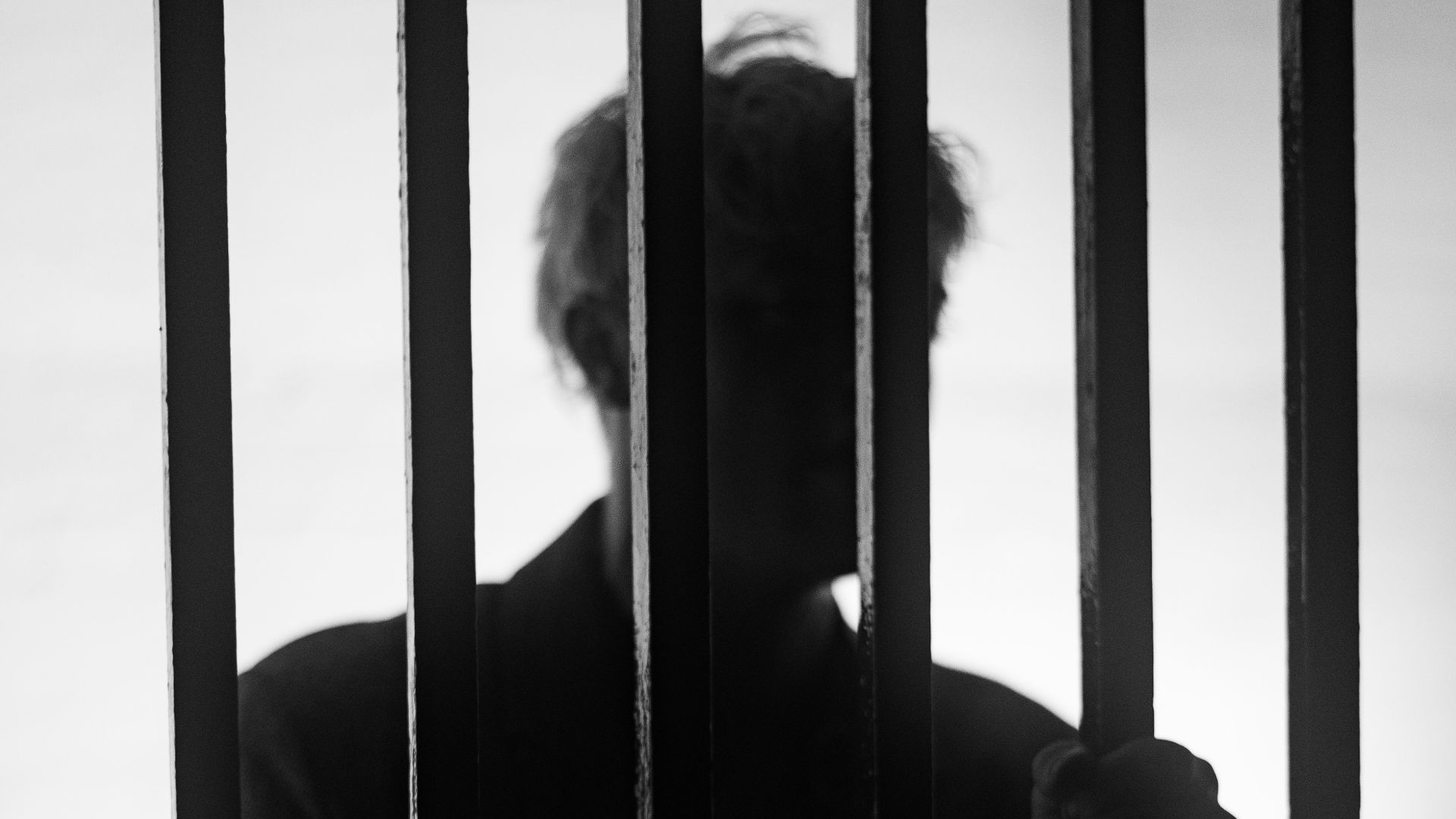 a man standing behind bars in a jail cell