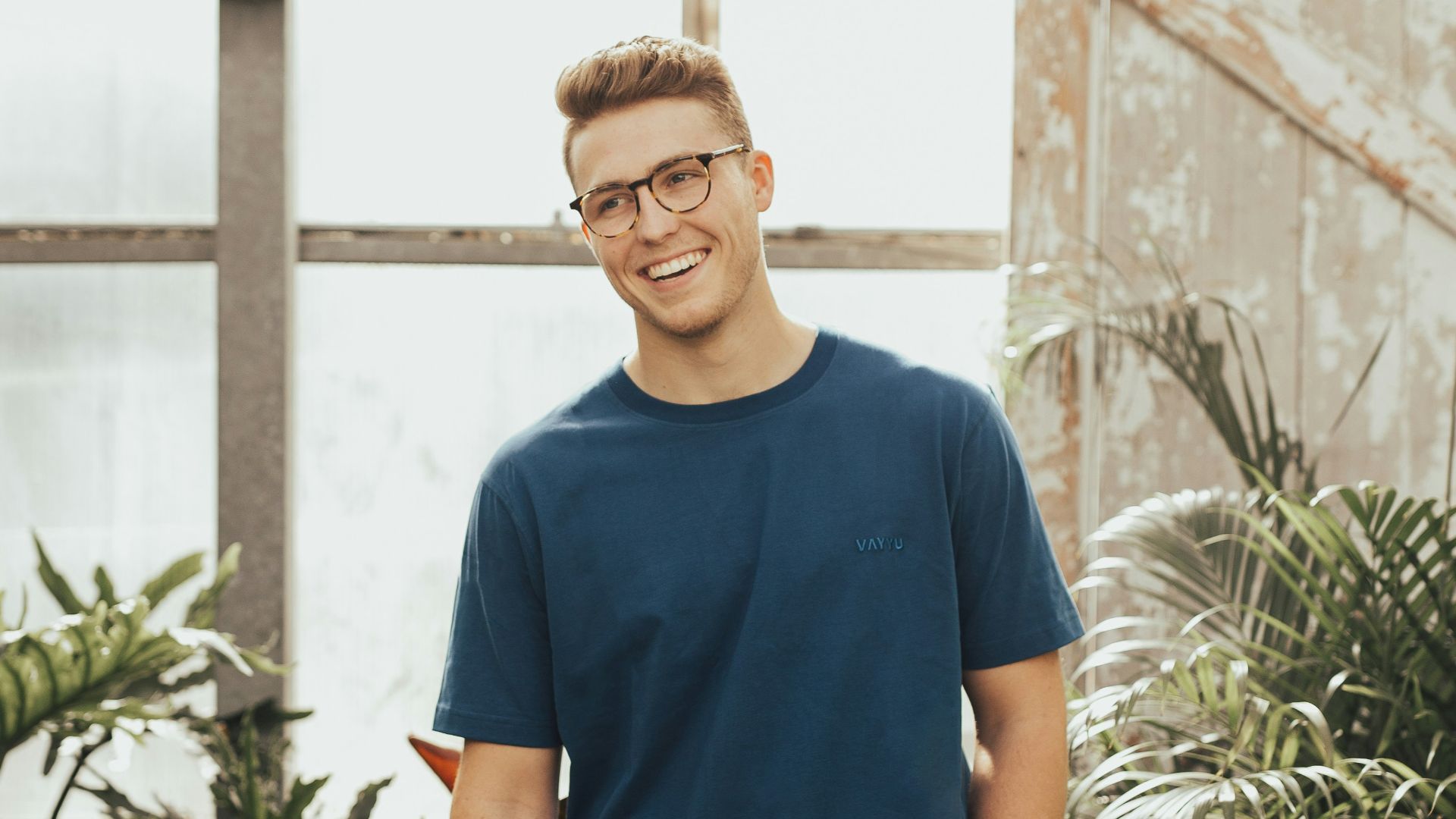 man in blue crew-neck top standing near plants