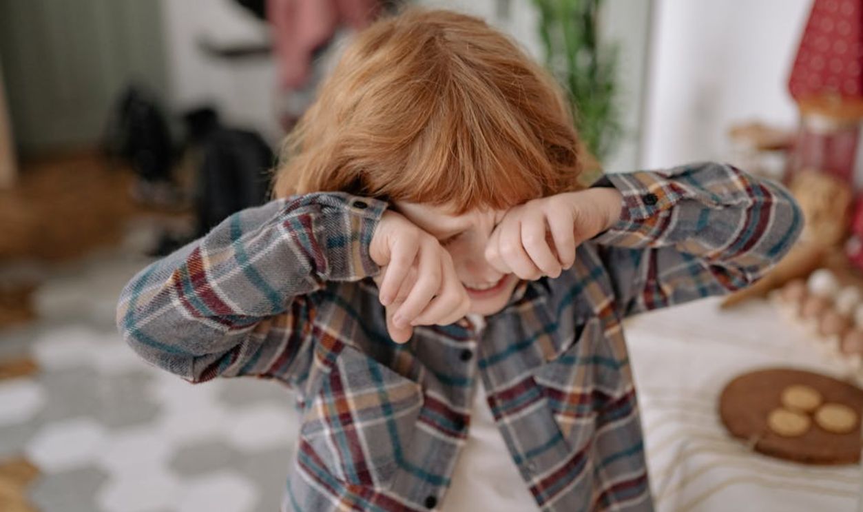 A Boy Crying while Covering Eyes