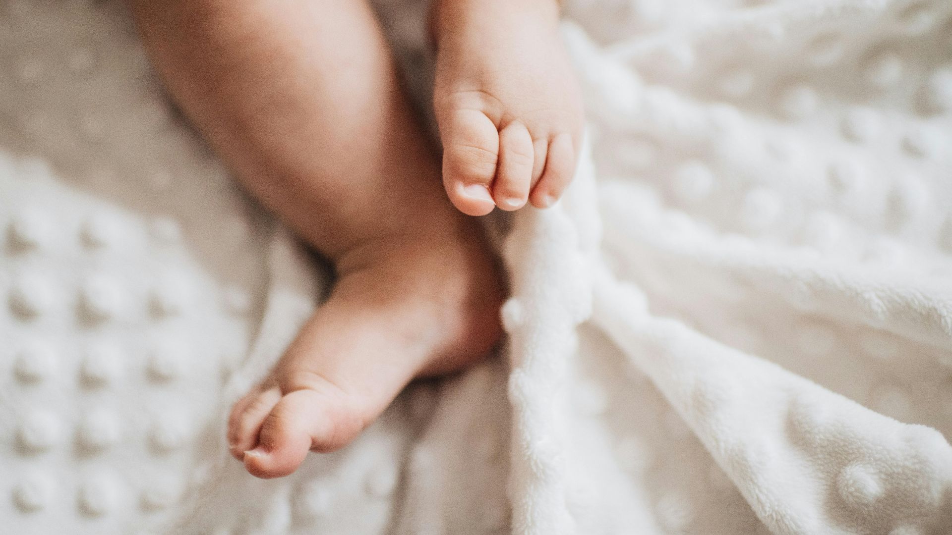 Close-up of baby feet on a textured white blanket, evoking warmth and innocence.