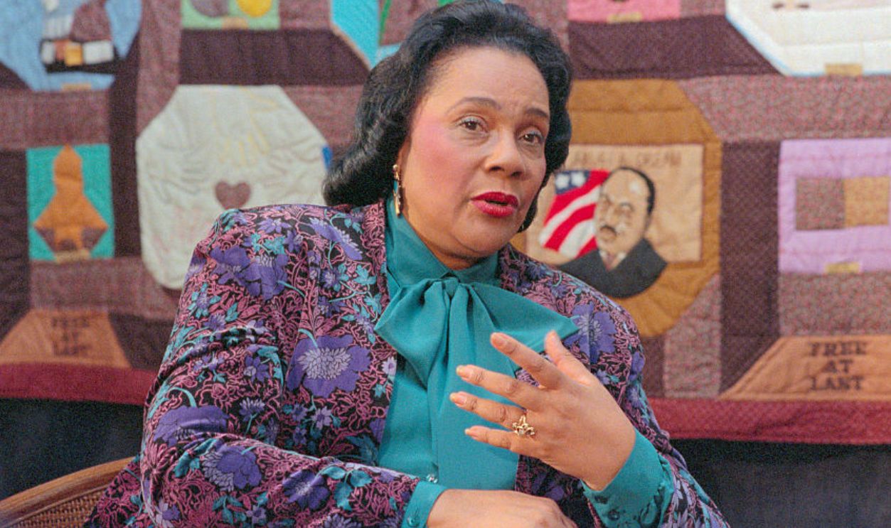(Original Caption) Atlanta. With a quilted portrait of her late husband Martin Luther King Jr. Looking over her shoulder, Coretta Scott King explains the philosphy of the Martin Luther king Jr. center for Non-violent Social Change during an interview 1/5. The King Center houses the late civil rights leader's crypt, a theater, meeting facility, offices and a museum with an Annual budget of 3.2 million and 60 million employees.