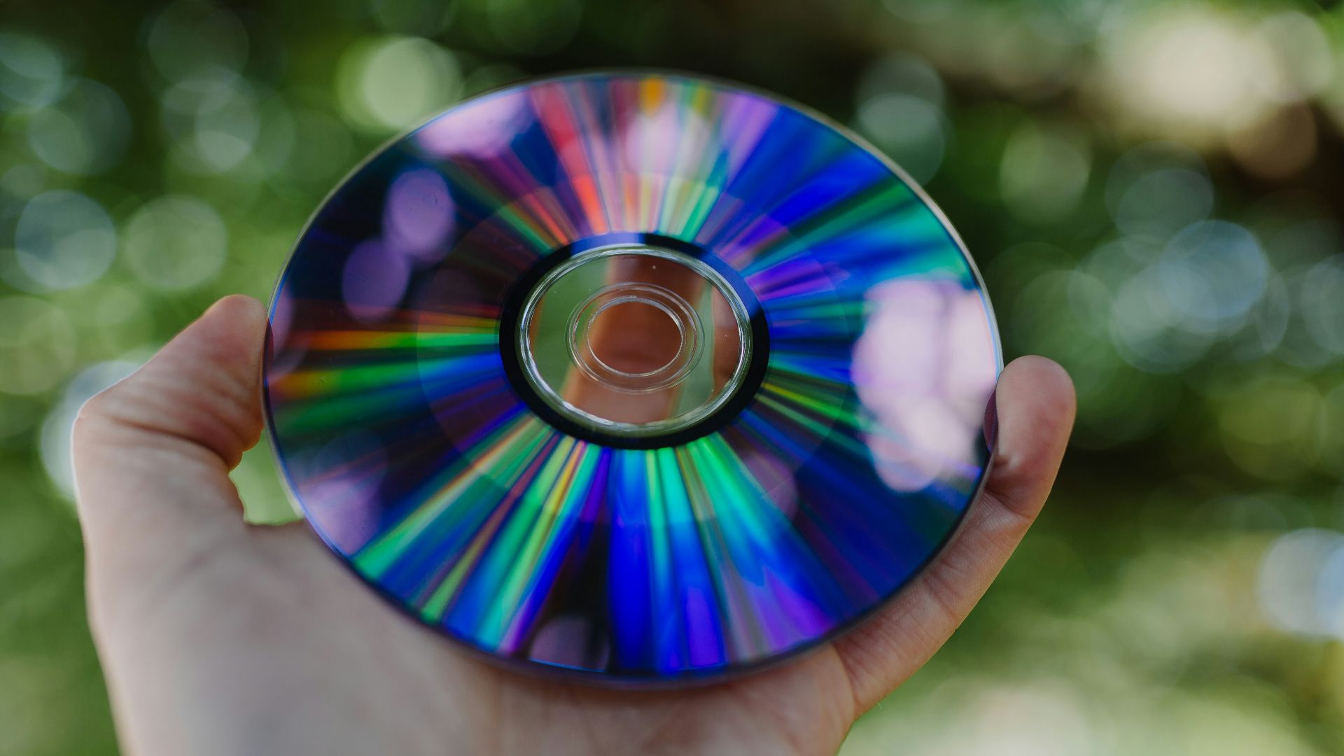selective focus photography of person holding compact disc