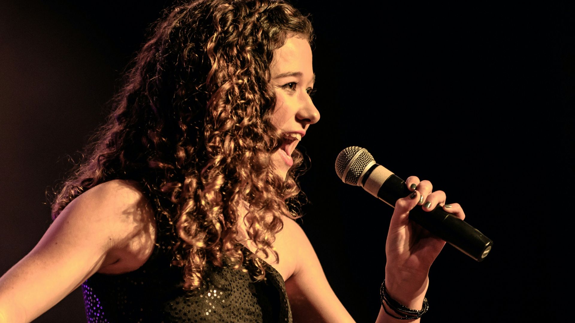 woman in black sleeveless dress singing