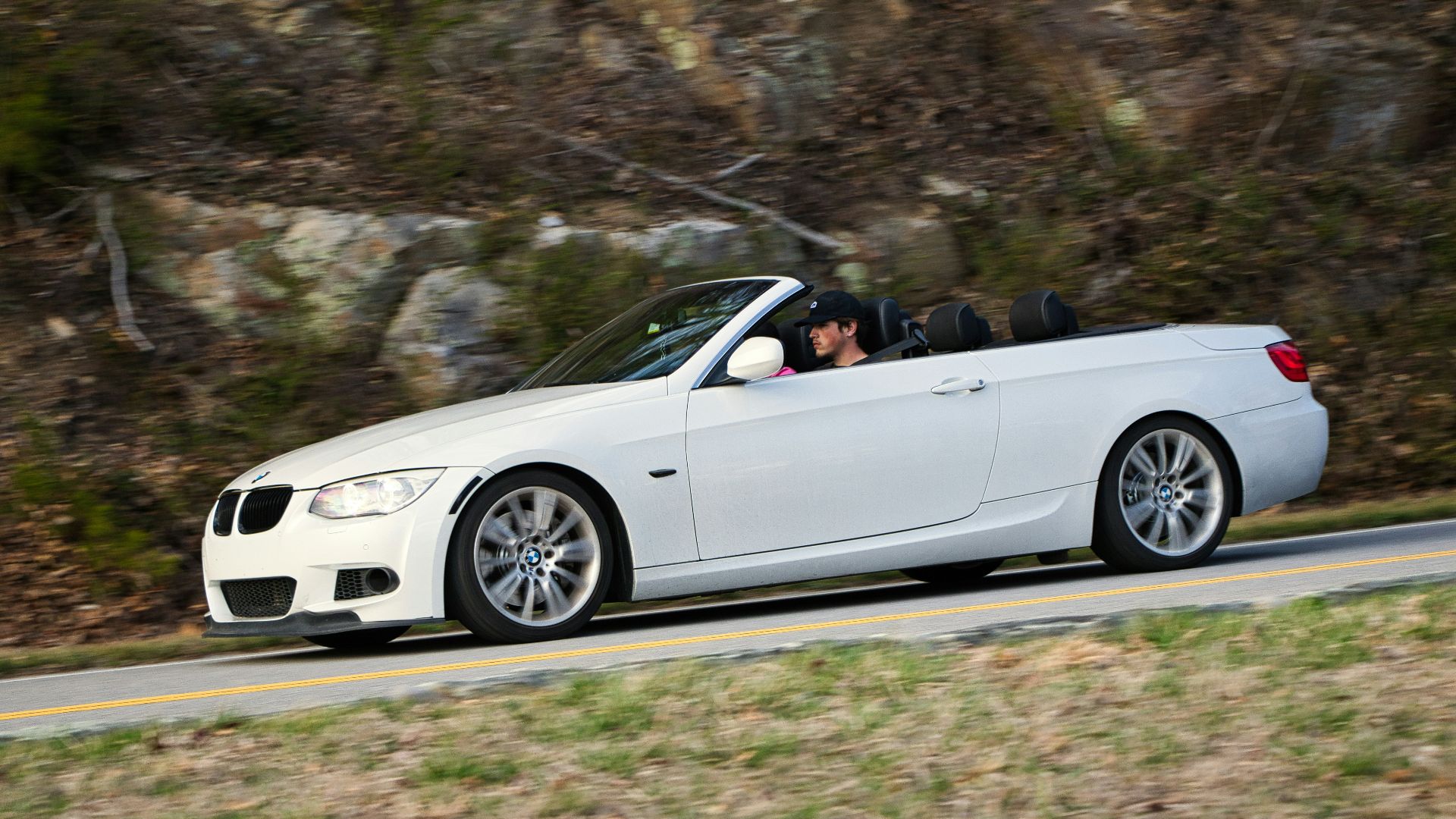 White convertible driving on a winding road.