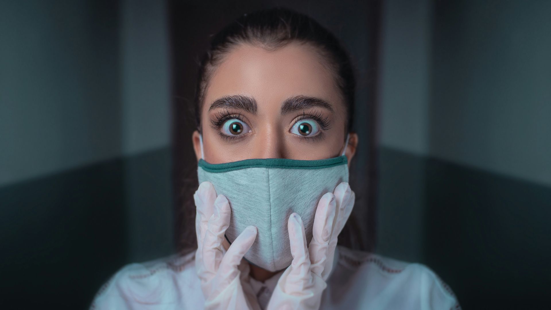 woman in white long sleeve shirt covering her face with blue and black face mask