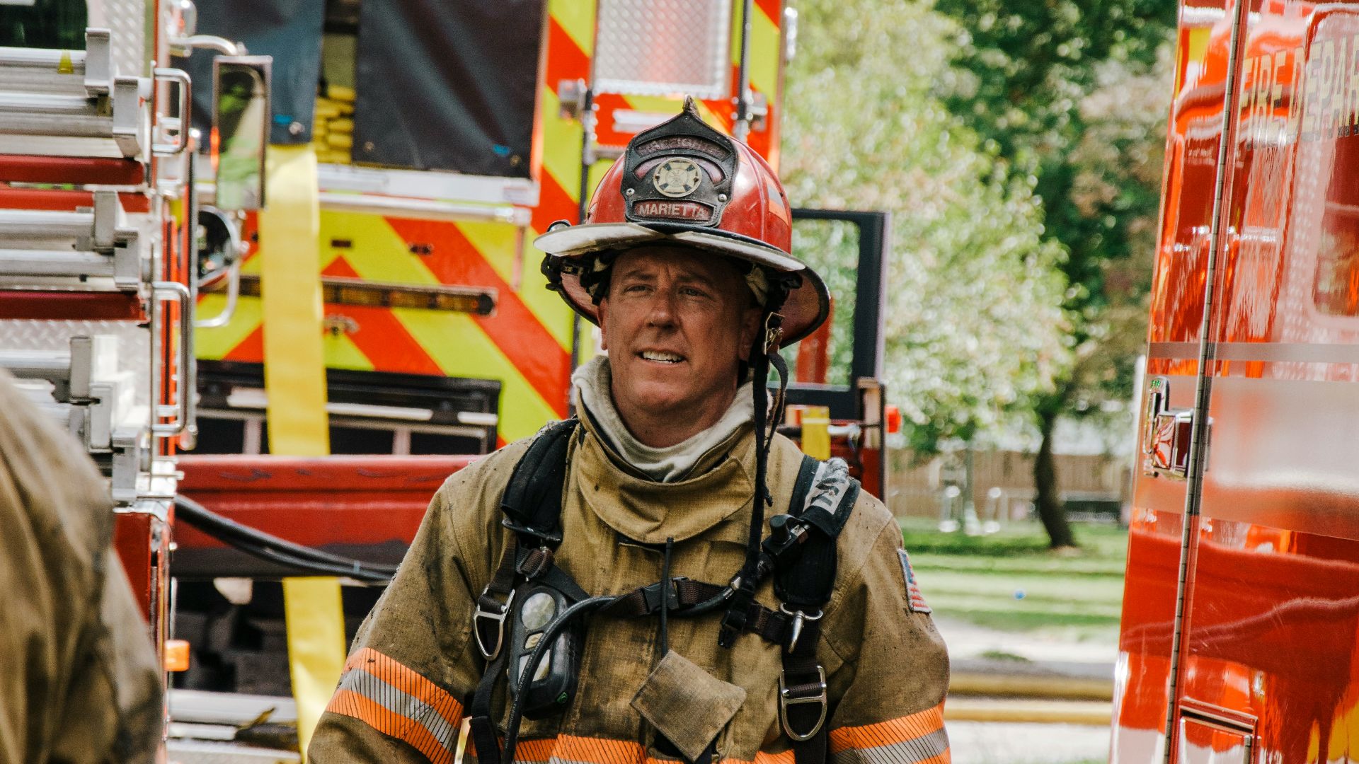 a fireman walking down a street next to a fire truck