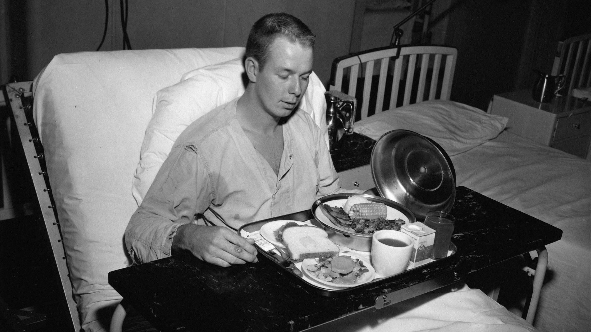 A man in a hospital bed eating a meal