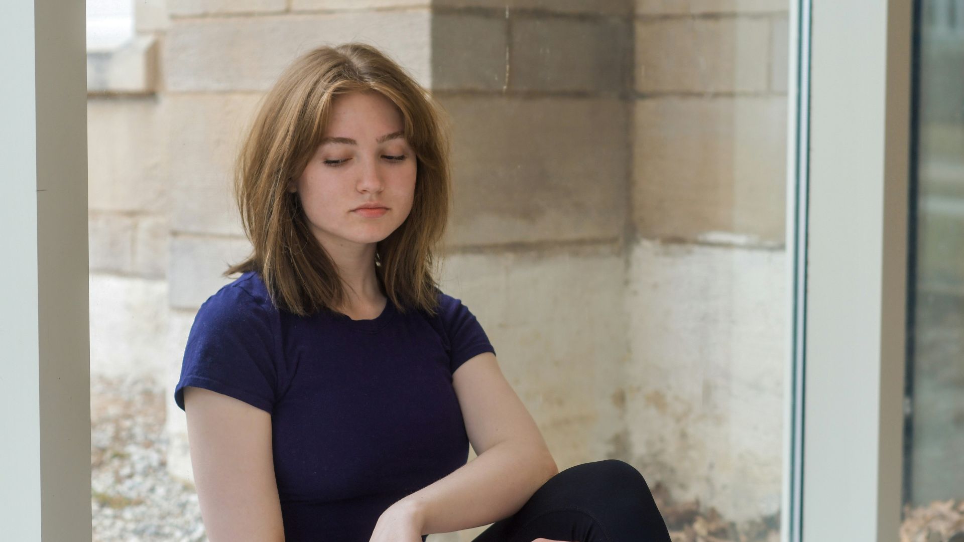 woman in black crew neck t-shirt and blue denim shorts sitting on window