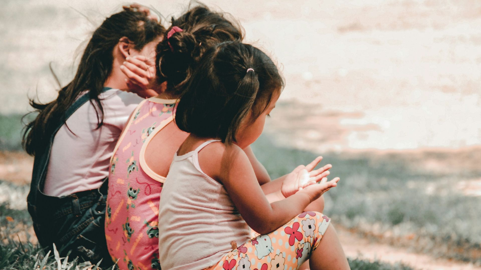 three children sitting on grass
