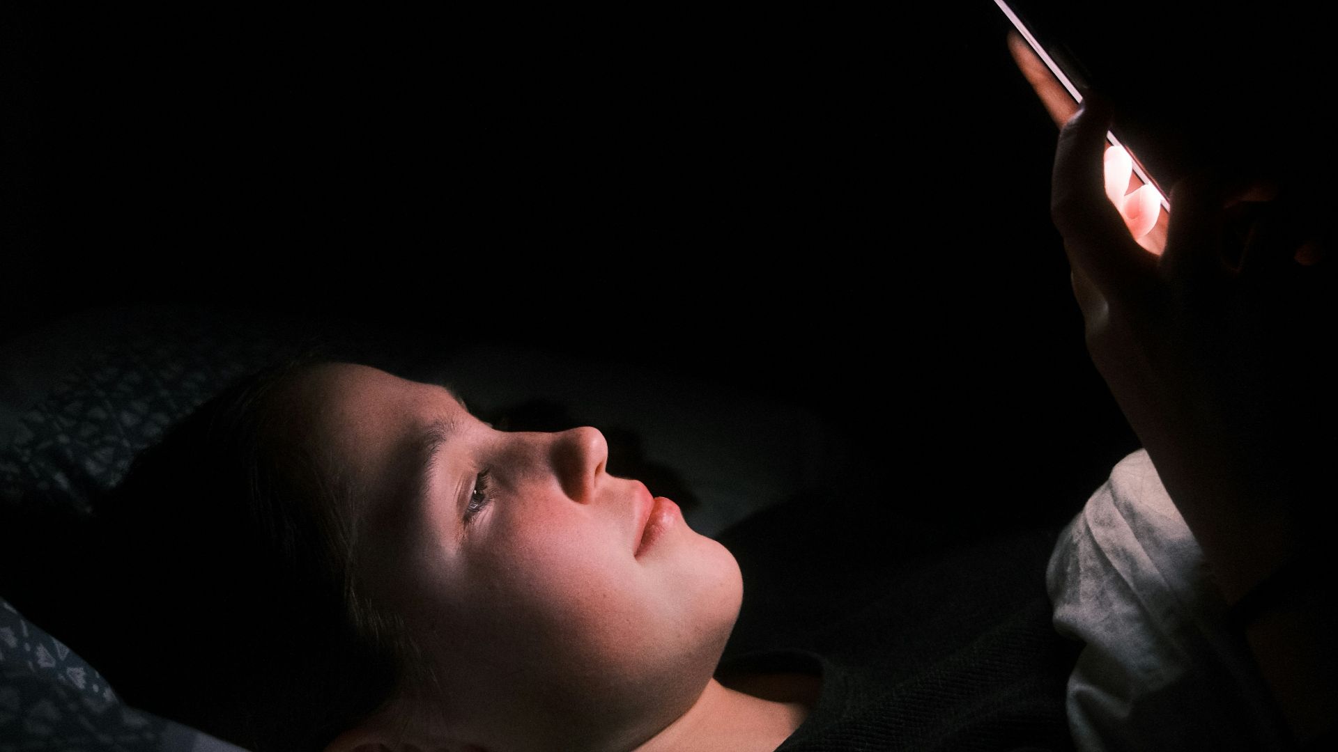 a woman laying in bed with a light on her face