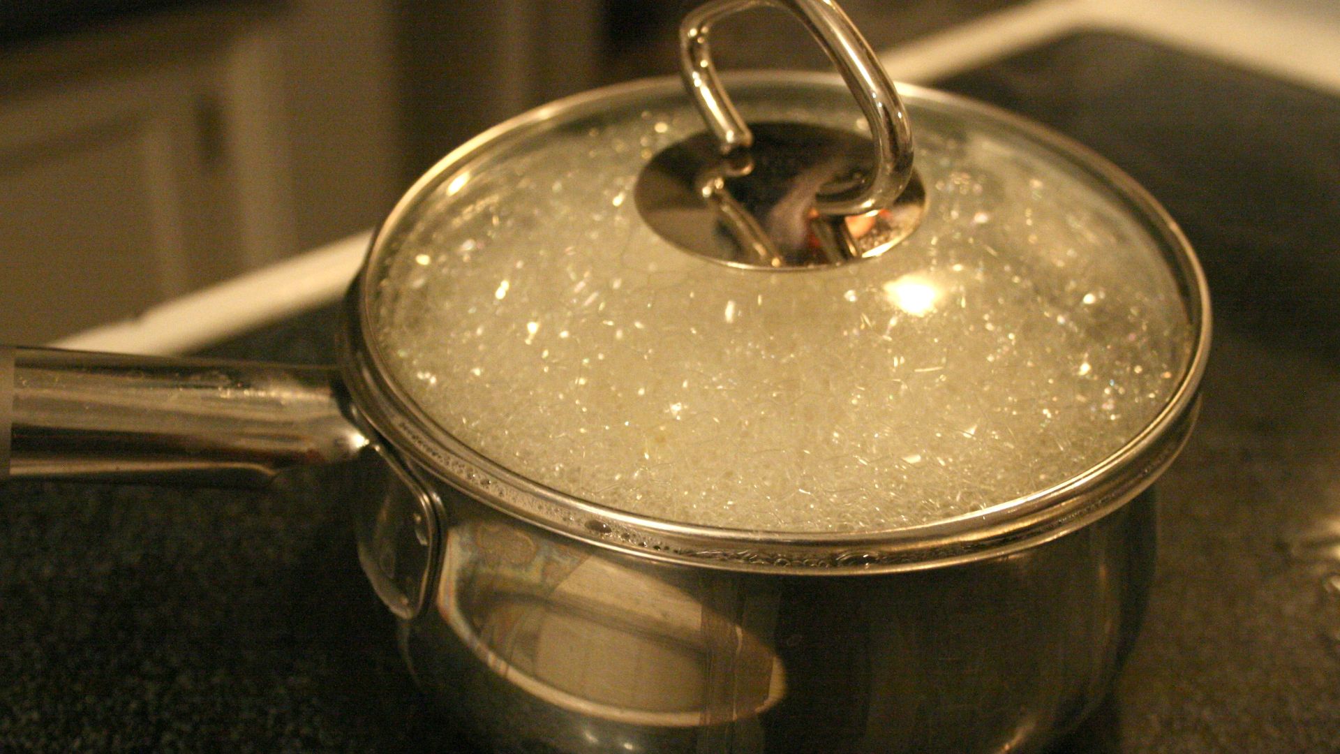 Water boiling in a pot while cooking rotini pasta on an electric stove.