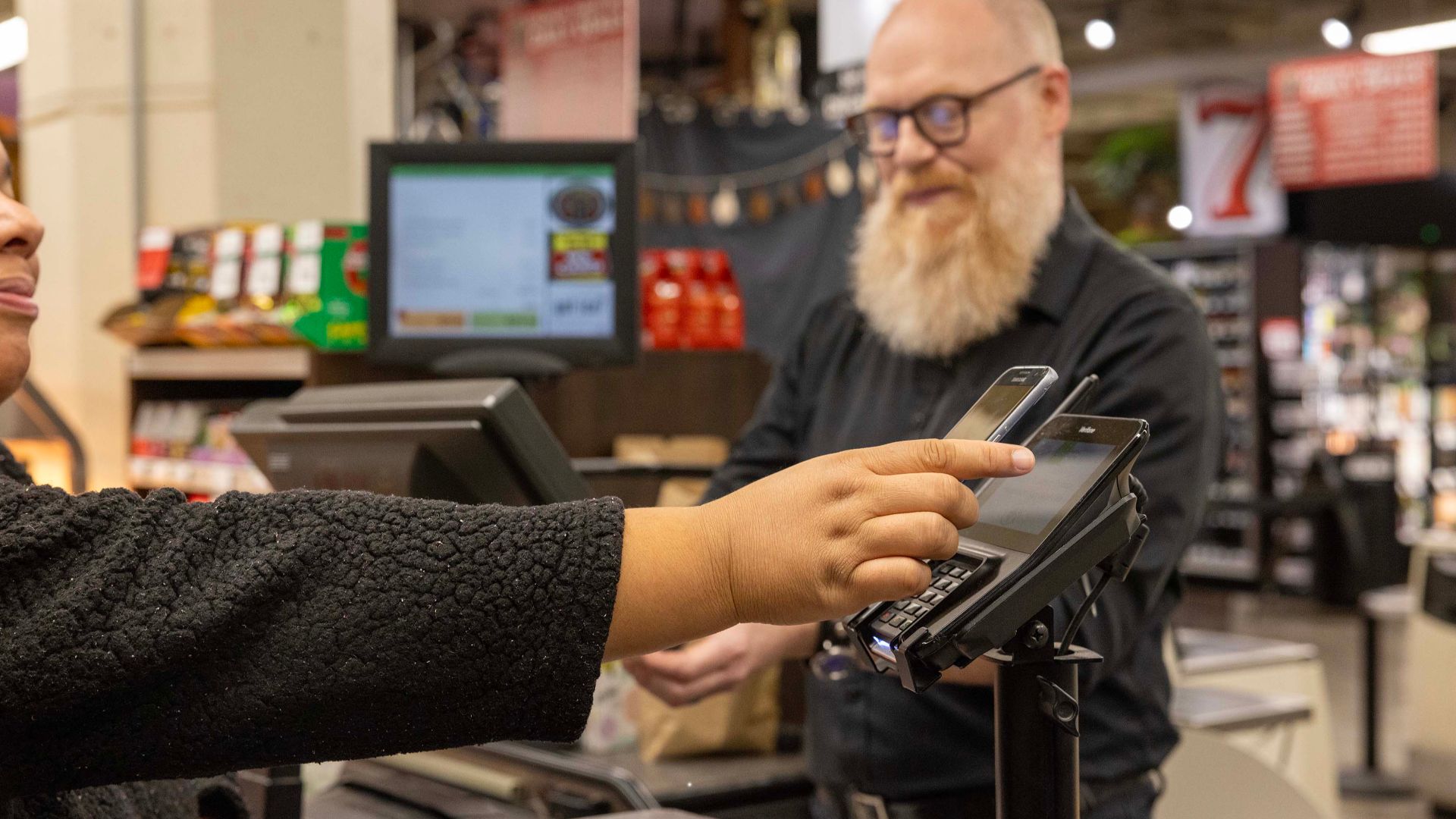 WIC shopper uses mobile phone application to pay for WIC foods while cashier looks on in a grocery store in Seattle, WA. (September 2024).