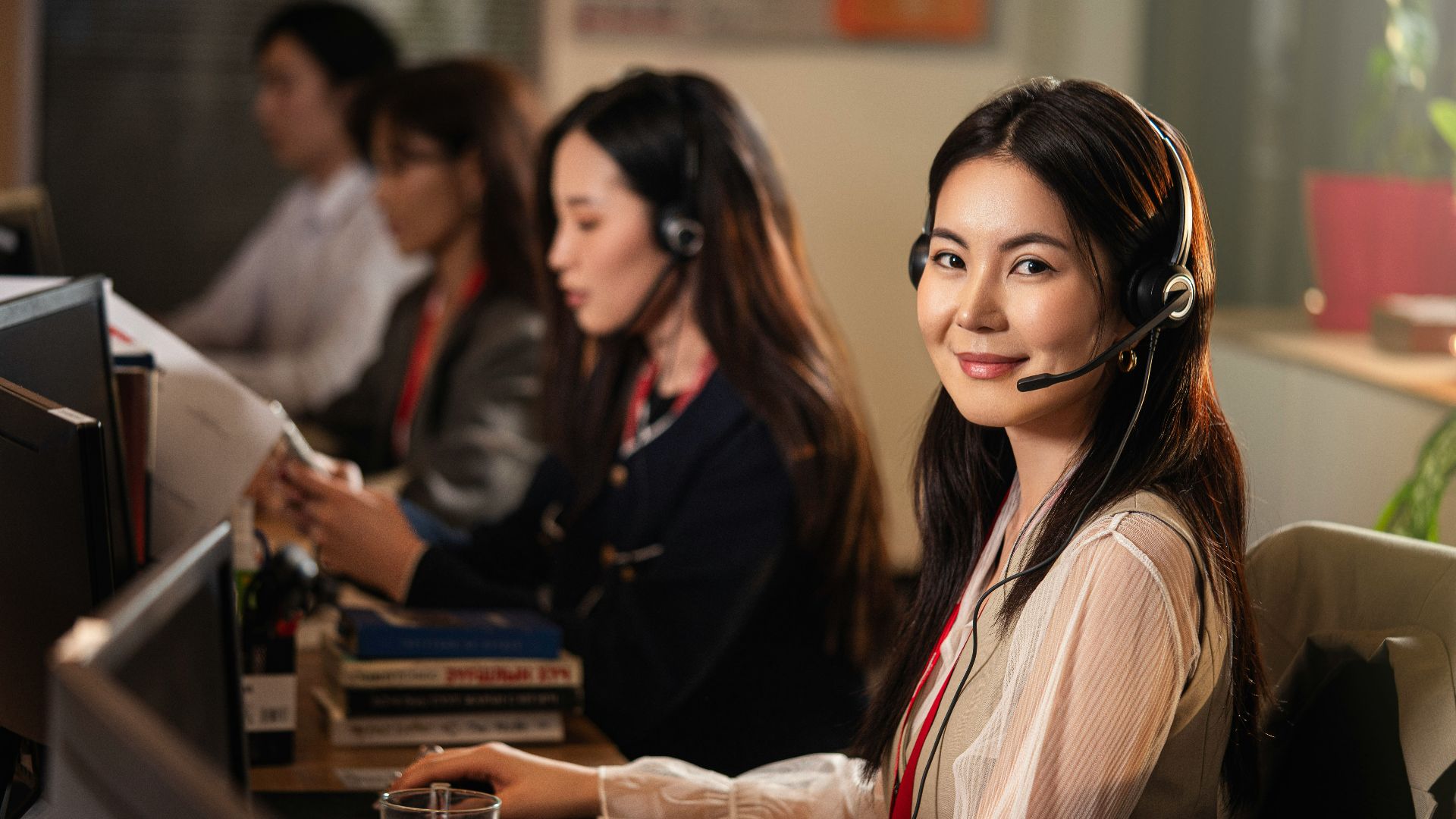 A smiling woman wearing a headset at a computer.