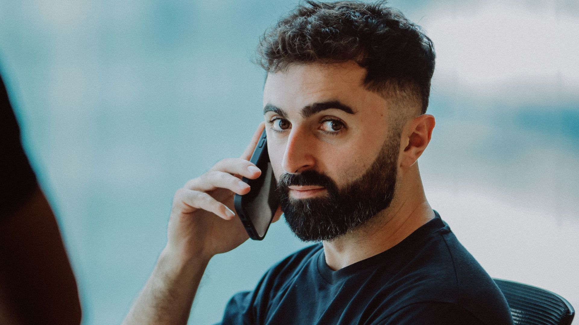 Man talking on phone at desk with laptop.