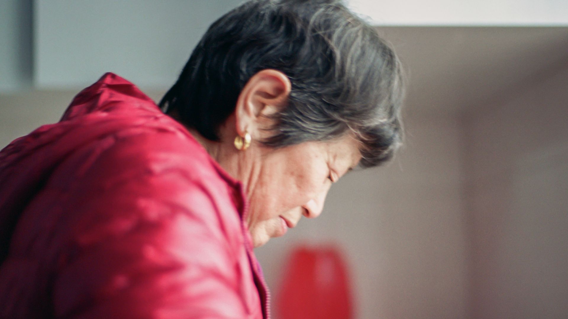 A woman in a red jacket preparing food in a kitchen