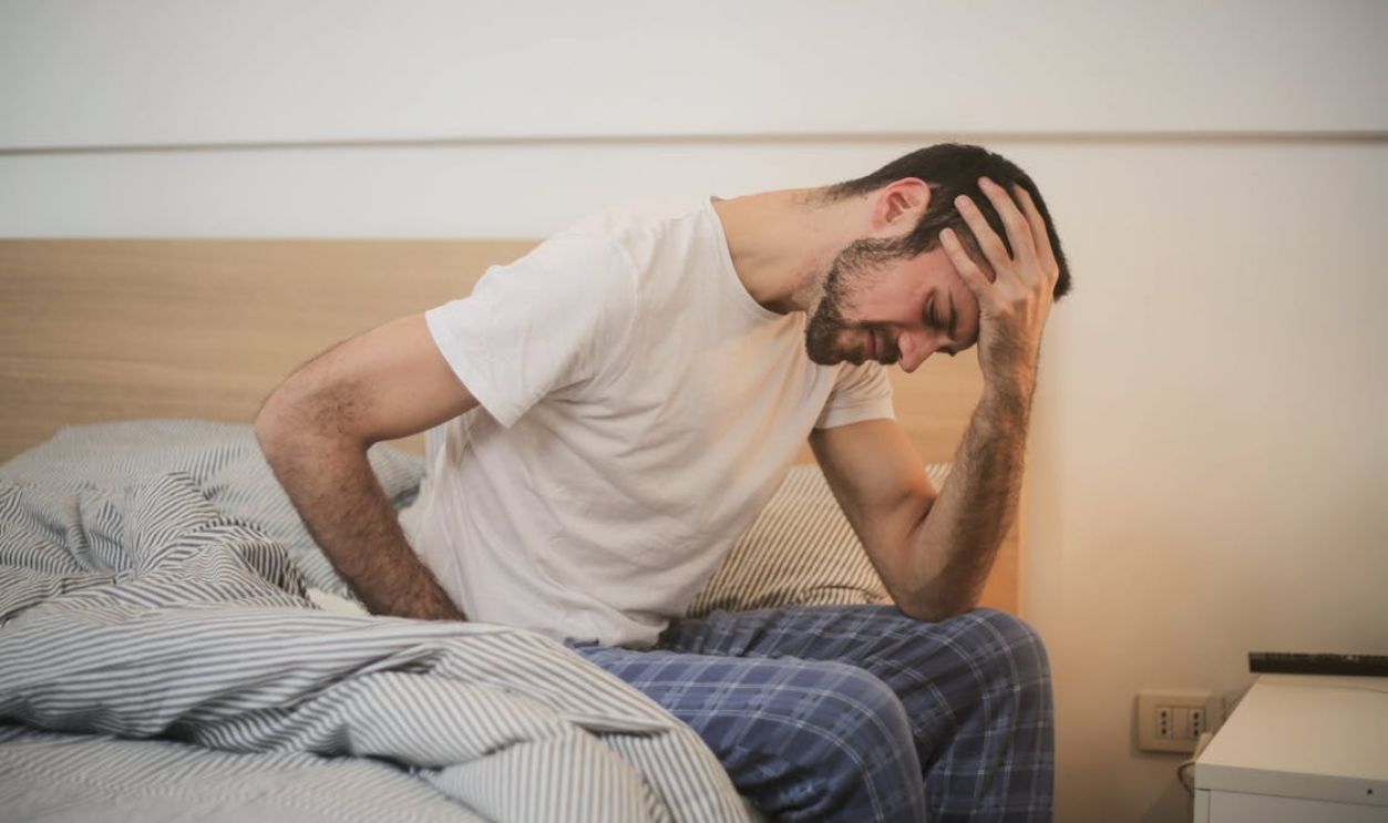 Young man in sleepwear suffering from headache in morning