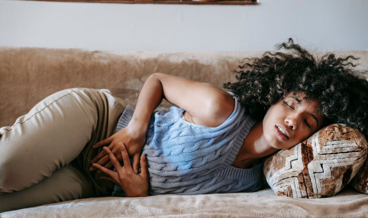 Woman Suffering from a Stomach Pain Lying Down on Couch