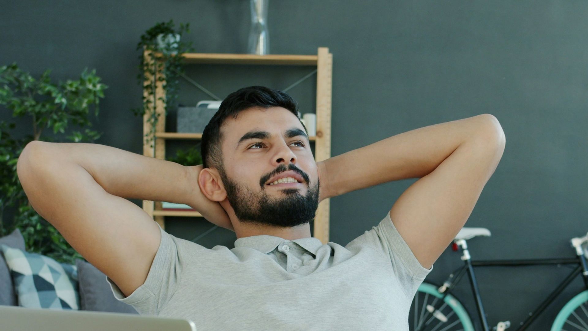Man relaxing at desk with laptop and bicycle.