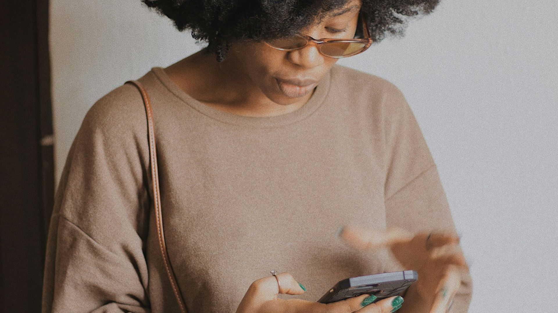 woman in brown long sleeve shirt holding smartphone