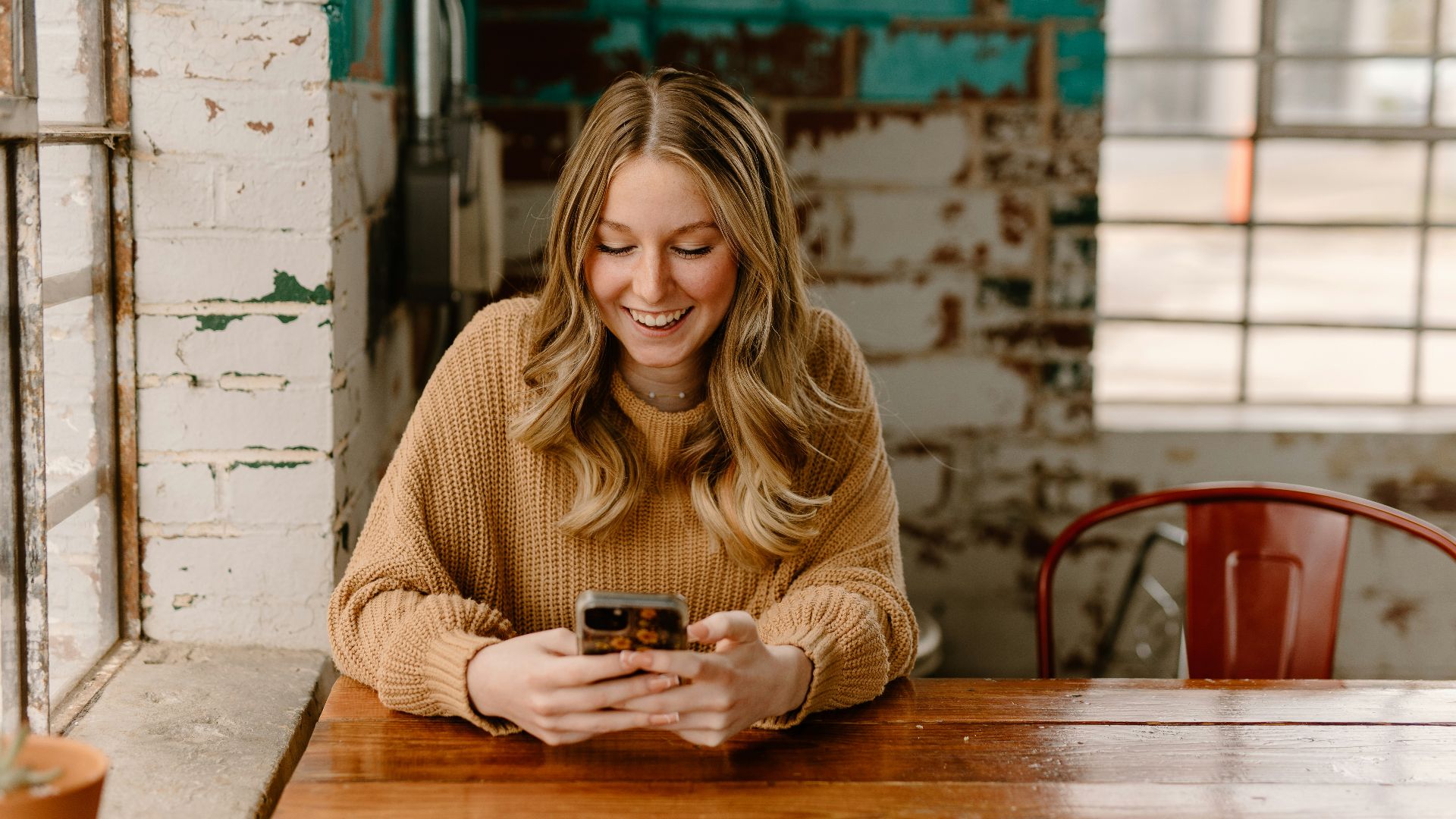 a woman sitting at a table looking at her cell phone