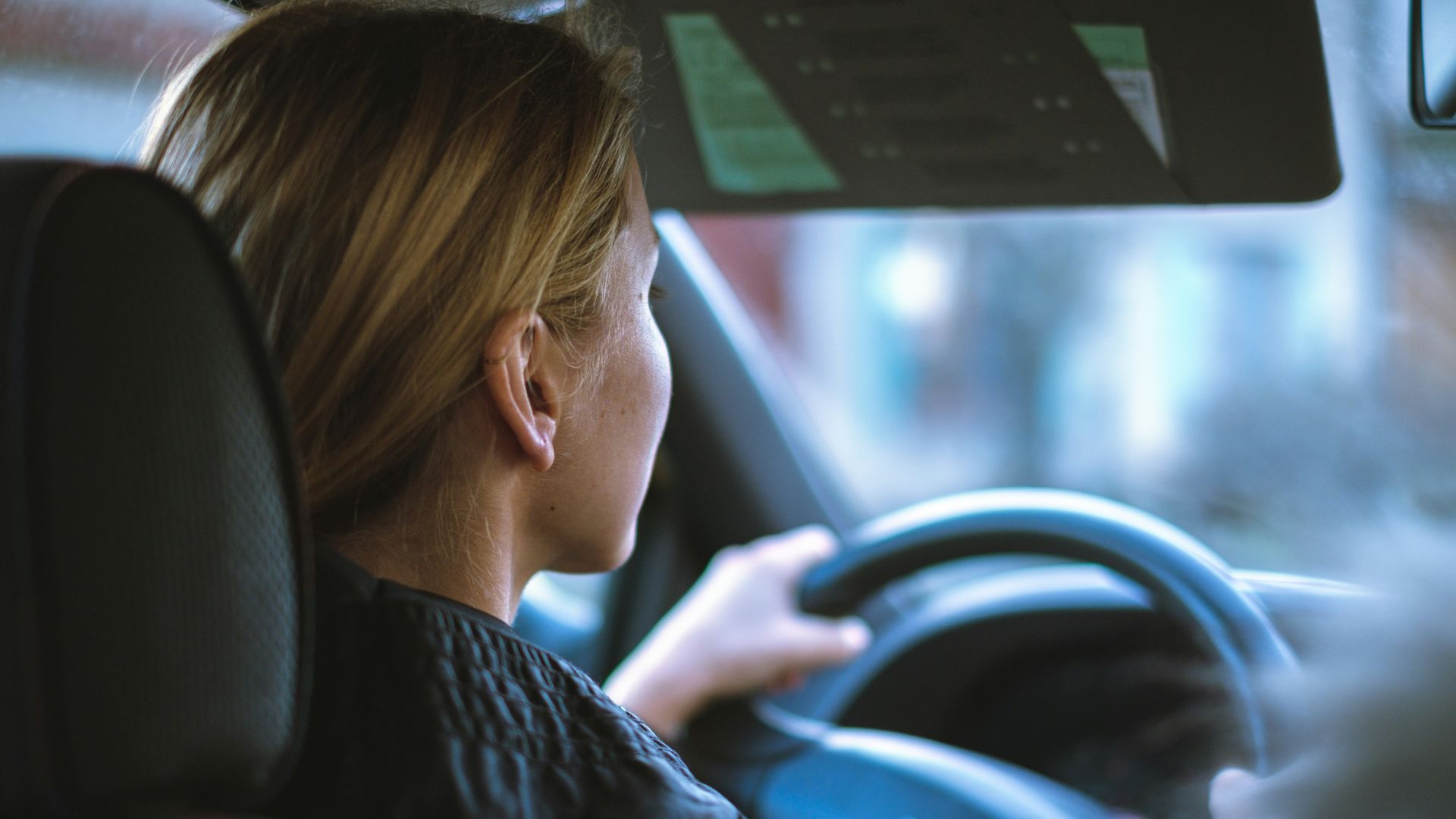 a woman sitting in a car with a steering wheel