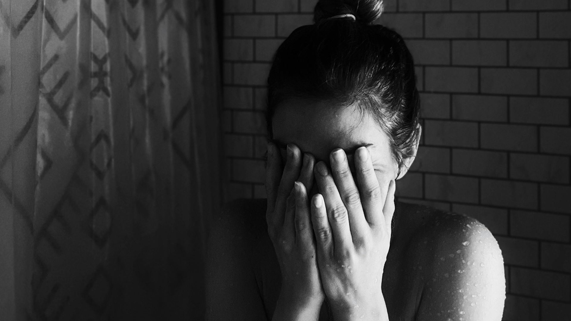 grayscale photo of woman covering her face with her hands