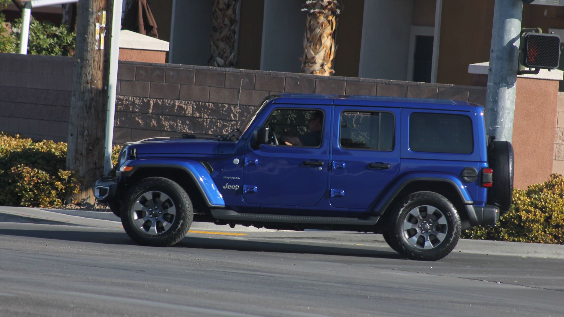 A dark-blue Jeep Wrangler JL turning onto West Lone Mountain road from North Rainbow Boulevard.