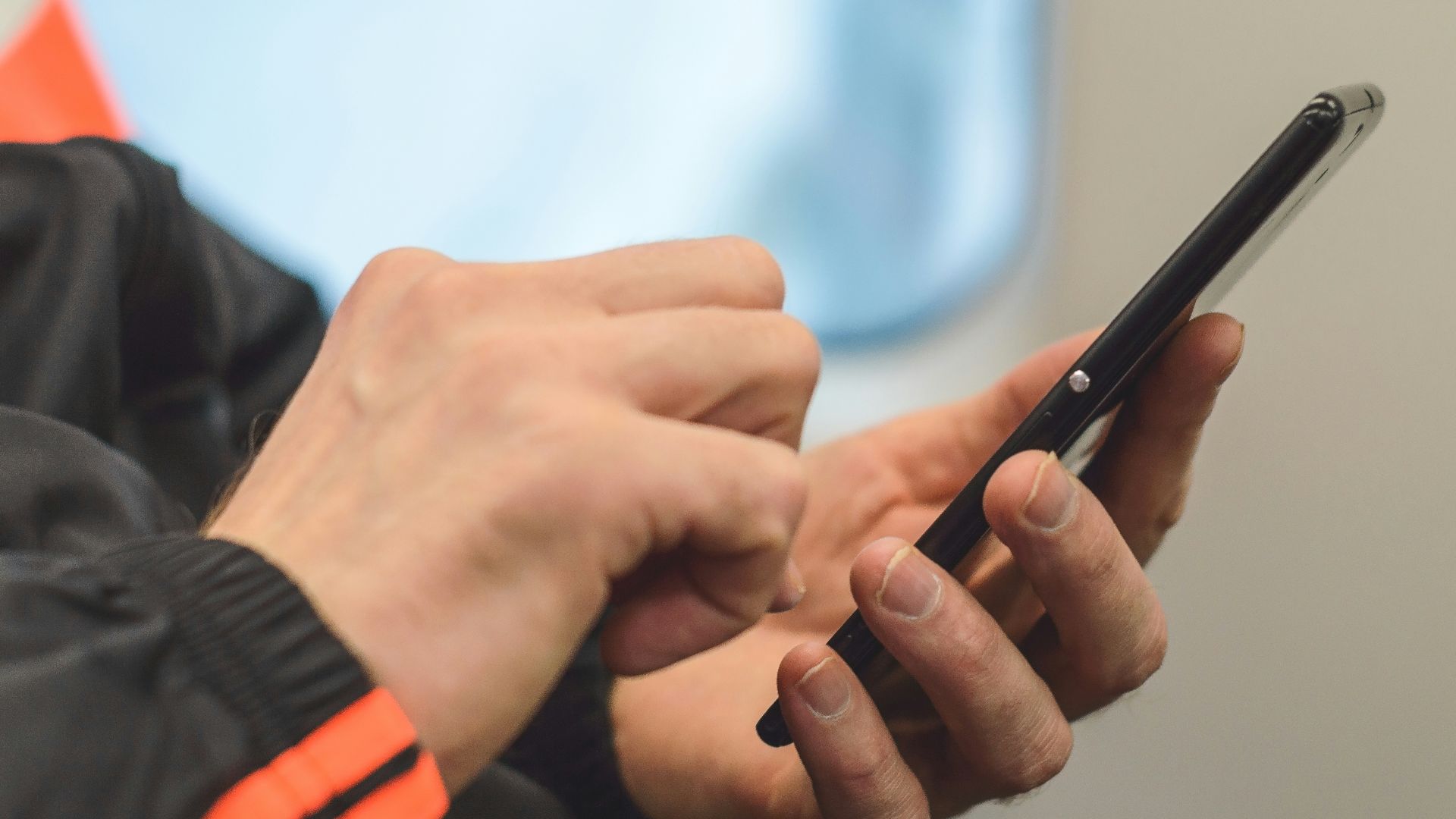 person in black and orange long sleeve shirt holding black pen