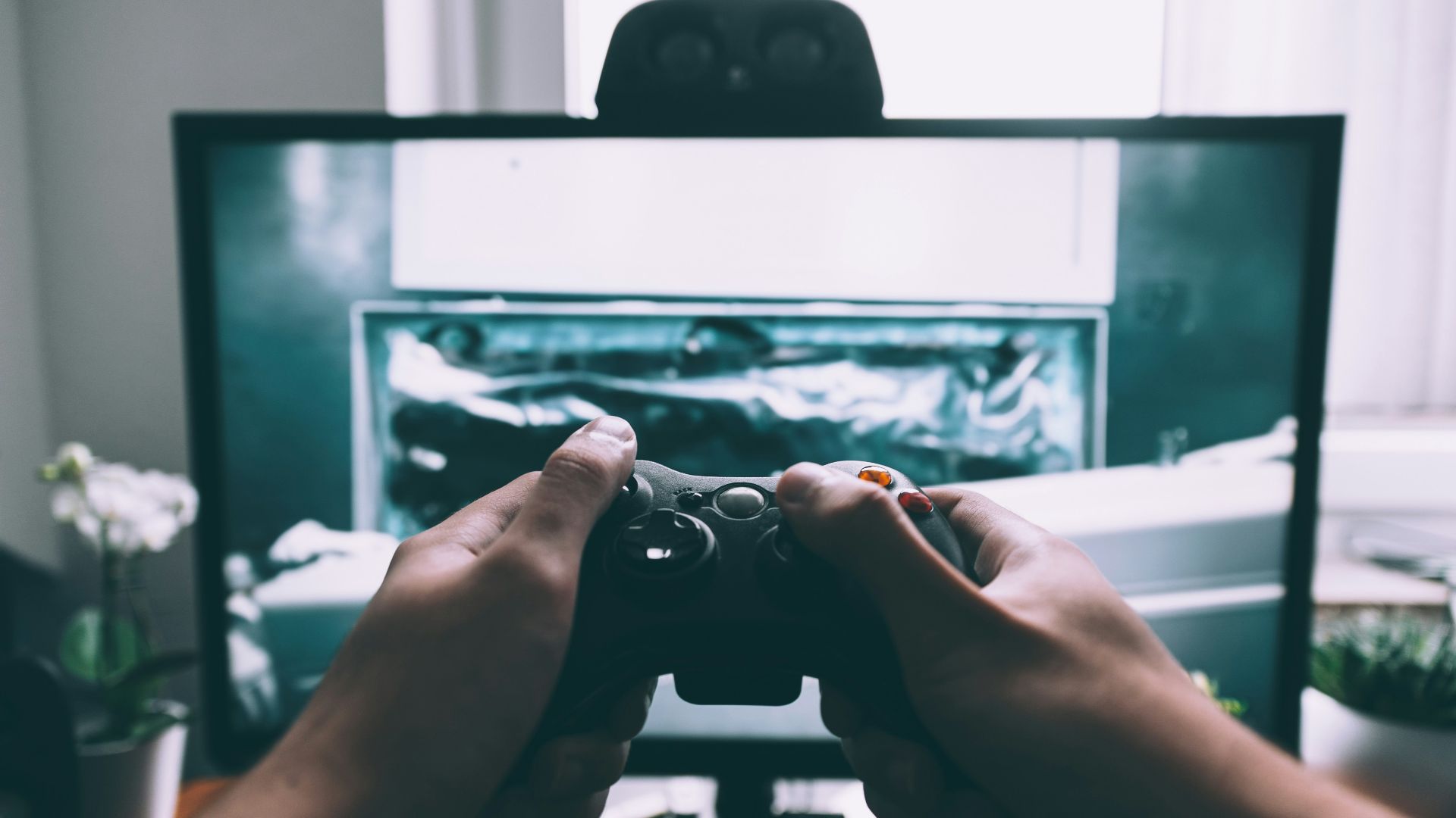 person holding game controller in-front of television