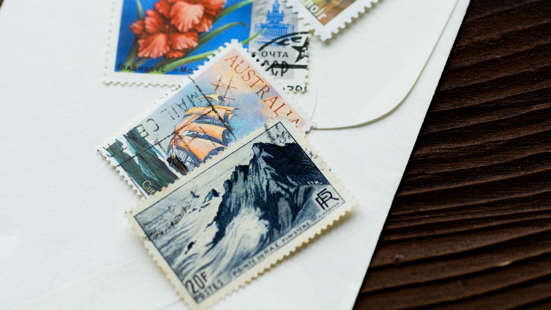 Envelope with stamps and spoon on a wooden surface