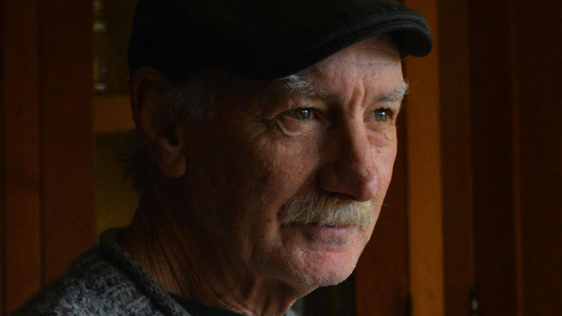 an older man wearing a hat in a kitchen