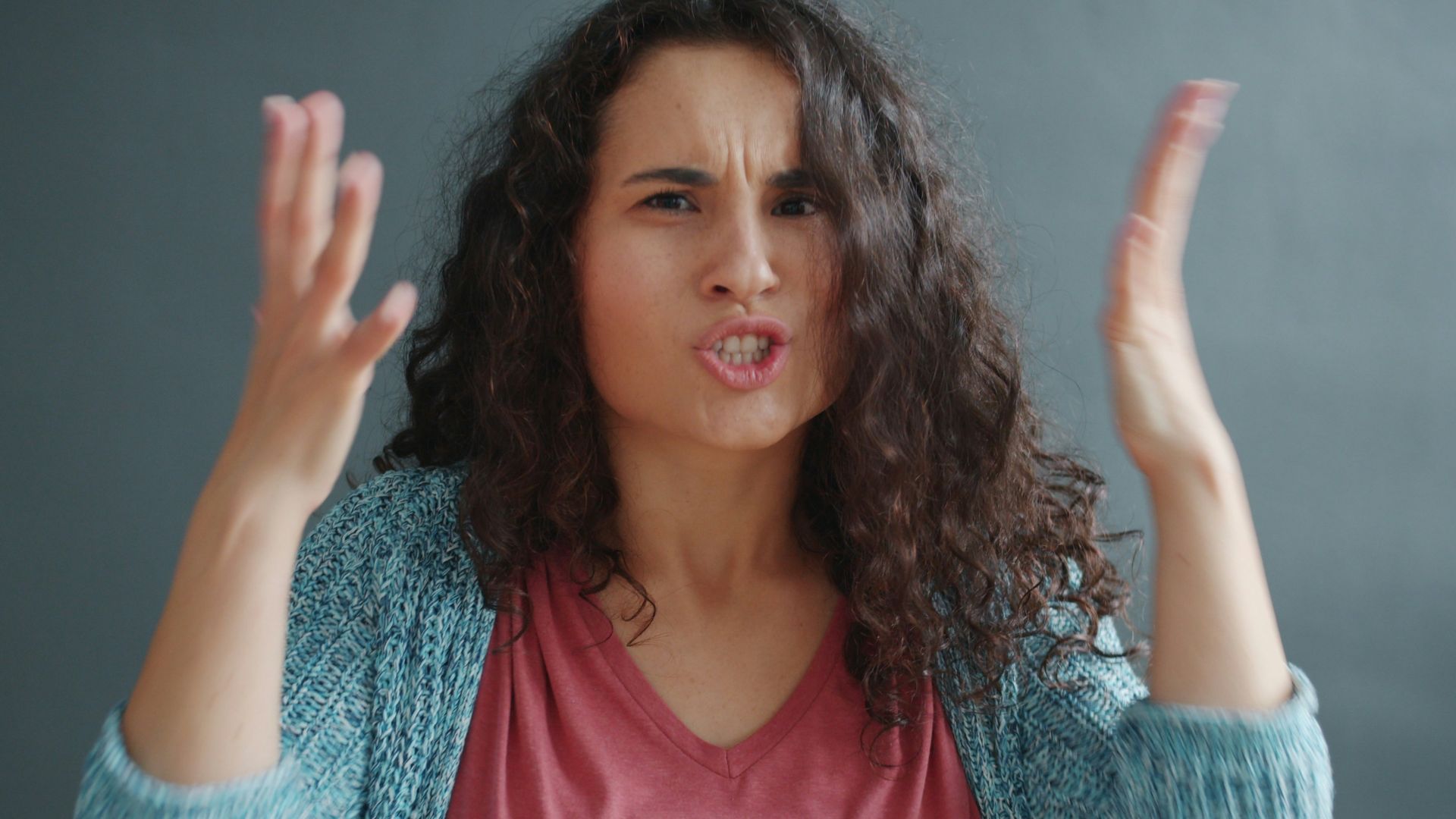 Woman with curly hair looking angry and frustrated.
