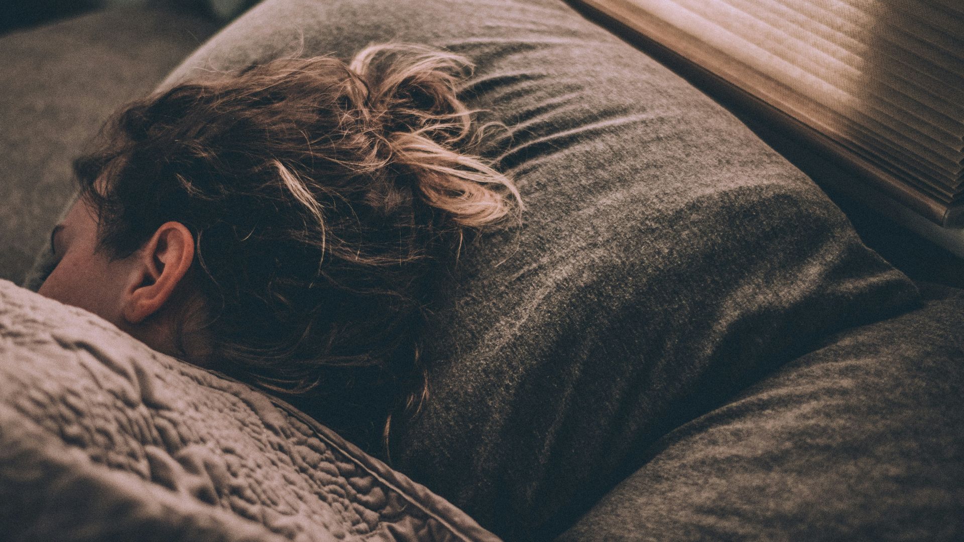 woman sleeping on bed under blankets