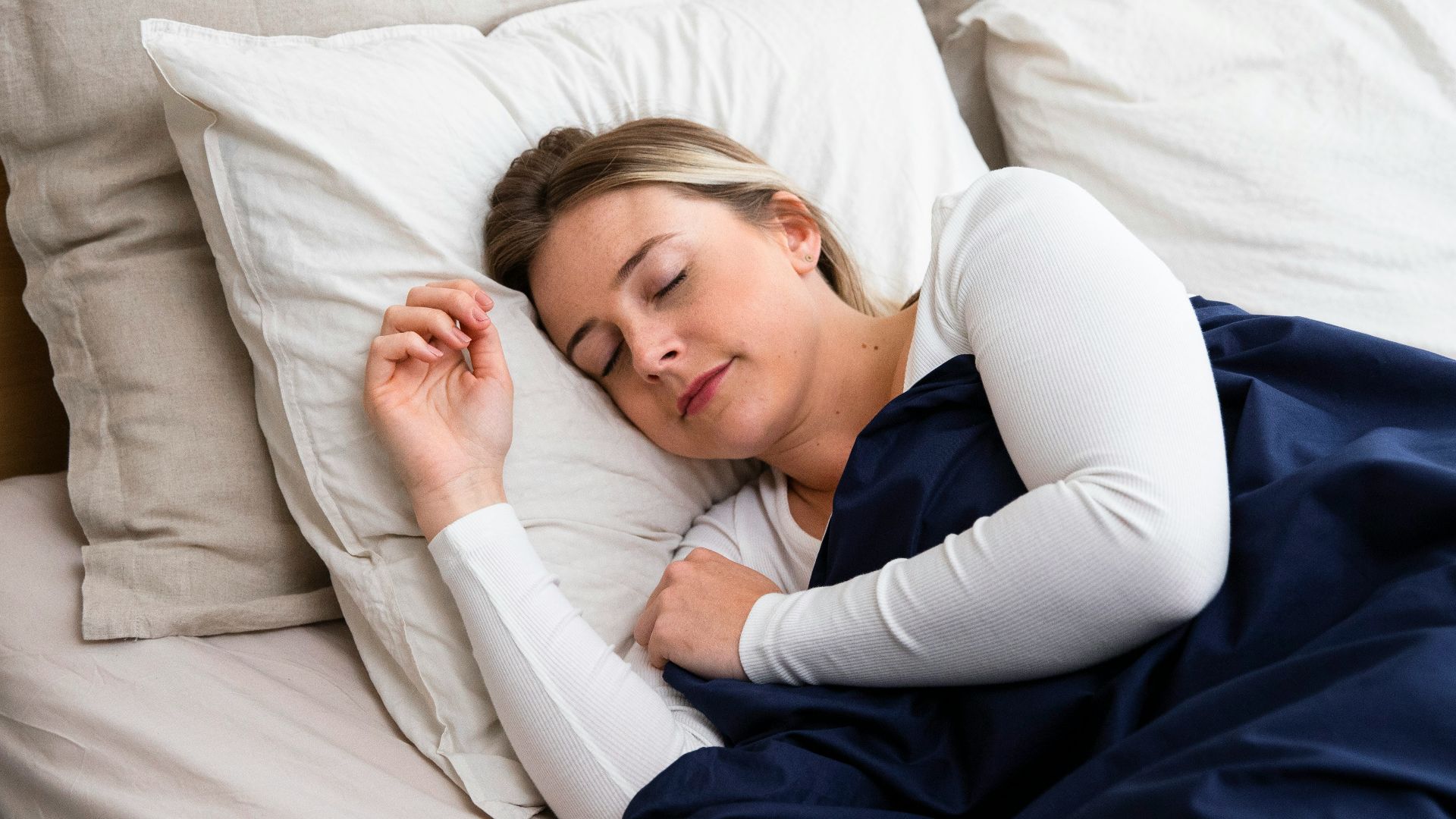 a woman sleeping on a bed with a blue blanket
