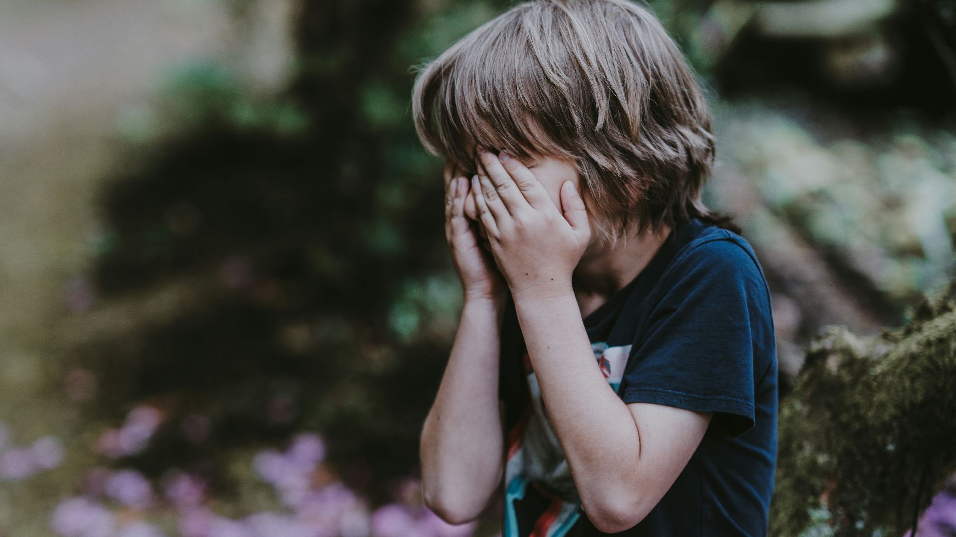 boy covering his face while standing