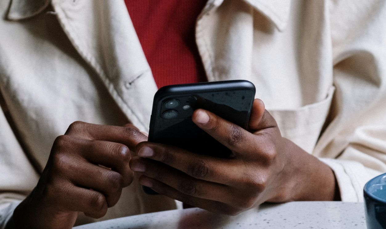 Woman in White Button Up Shirt Holding Black Smartphone