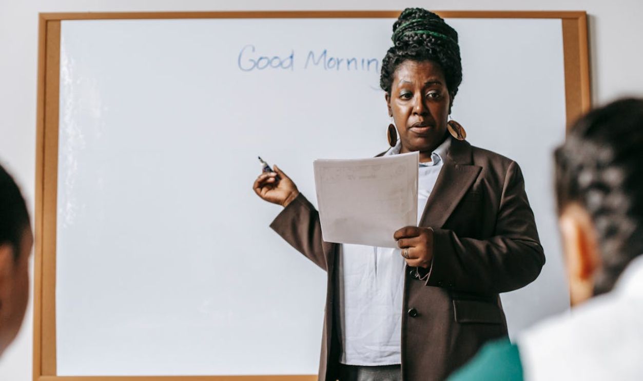 Focused black female teacher explaining class plan to pupils