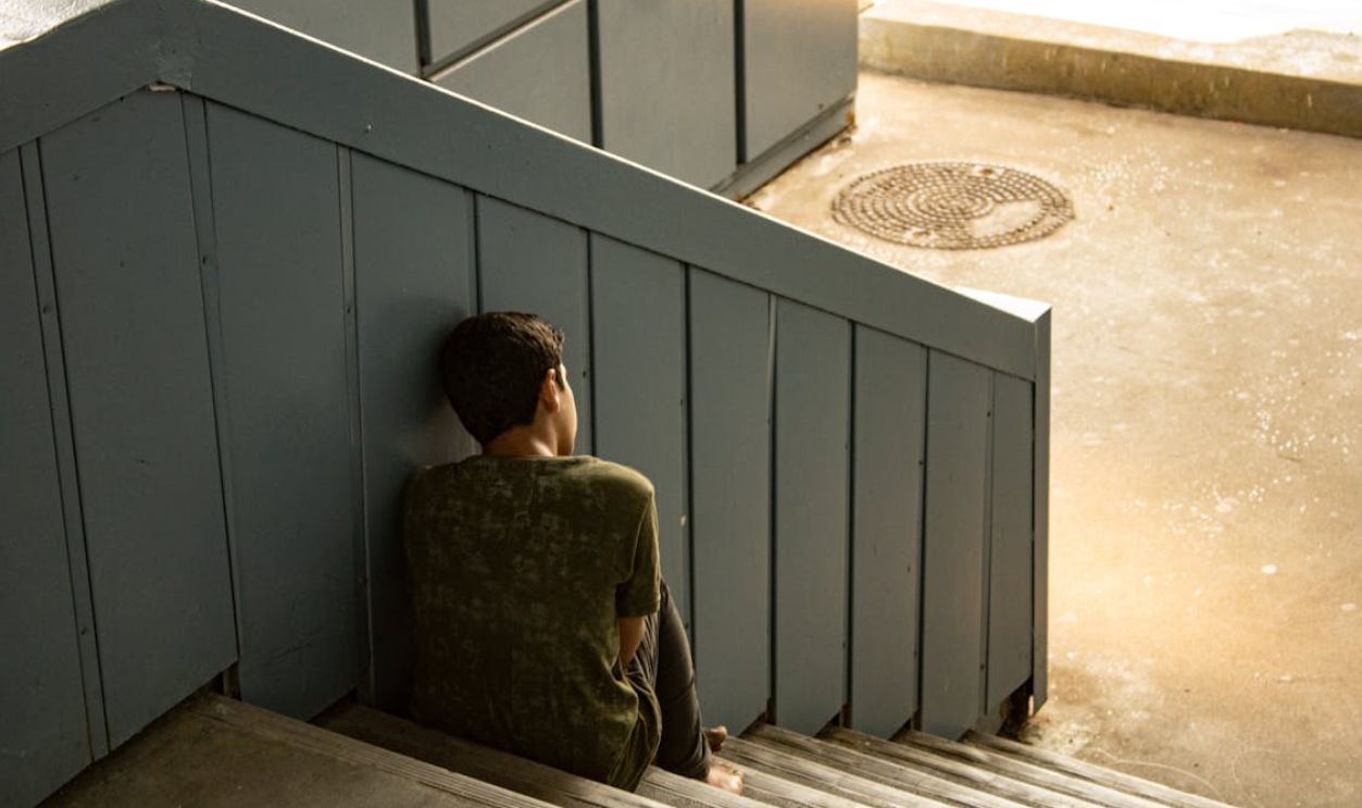 Back View Shot of a Young Man Sitting on the Stairs